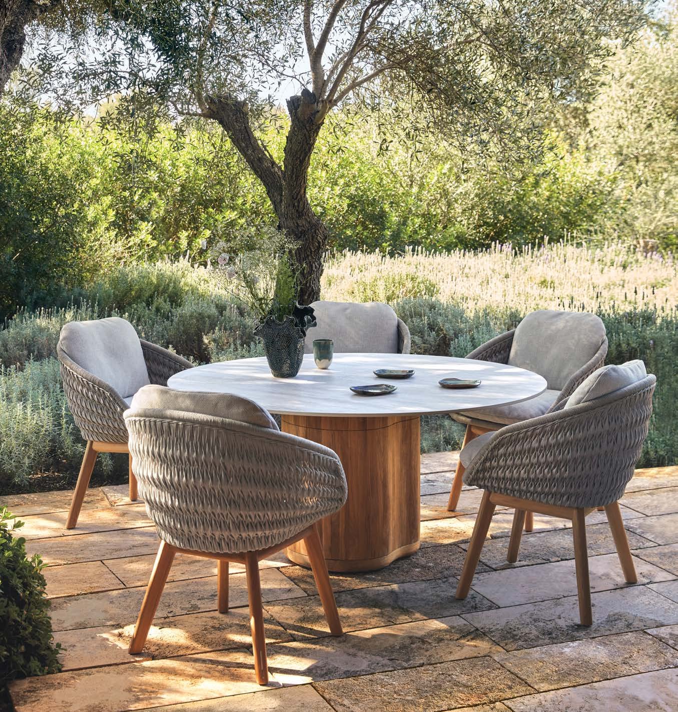 Manutti Ogado round teak table under an olive tree.